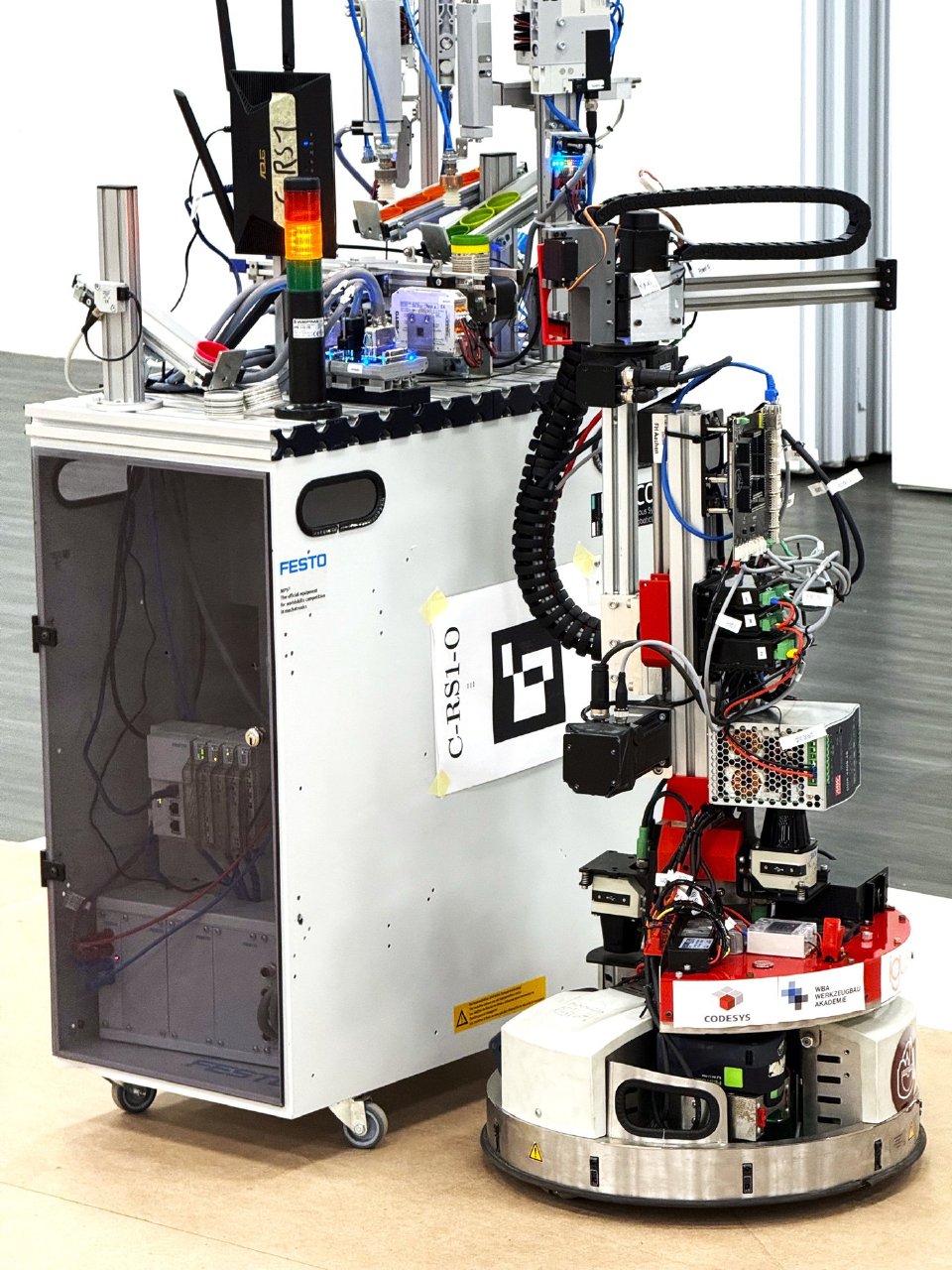 A Robotino alongside a Festo MPS production station. The vertical axis of the gripper and the camera above it are on the right.